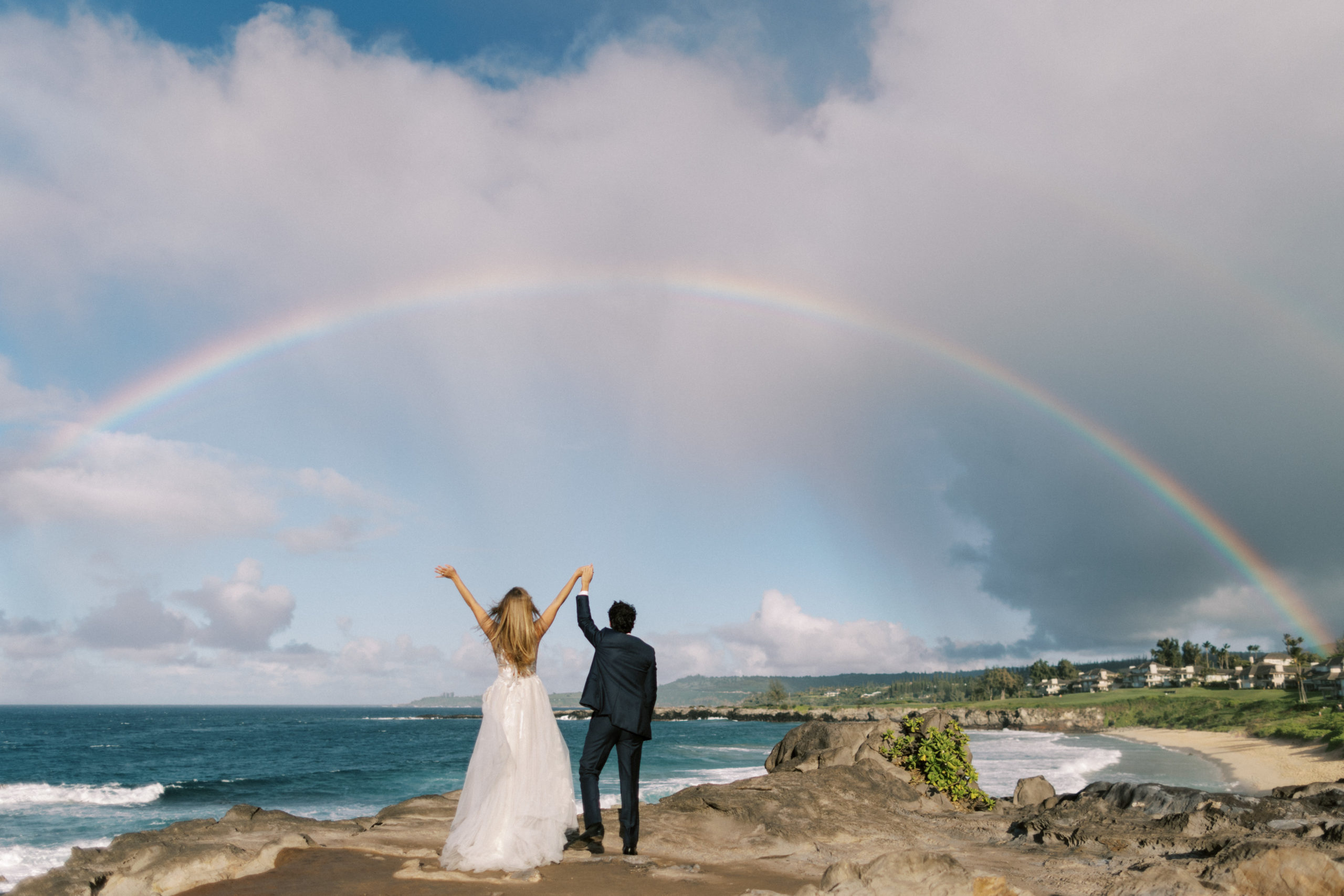 couple under rainbow during elopement photos at ironwoods beach in maui hawaii