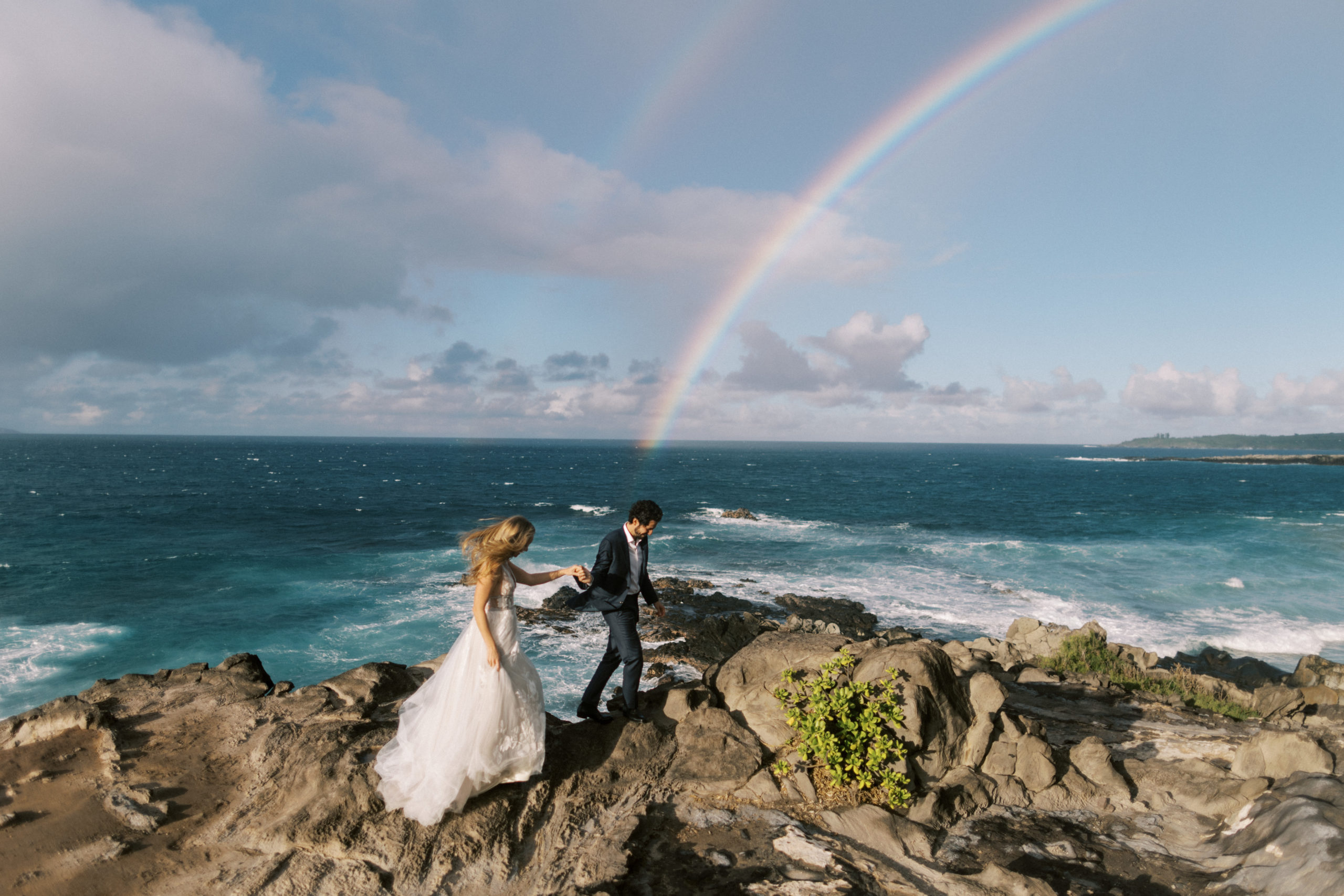 couple under rainbow during elopement photos at ironwoods beach in maui hawaii